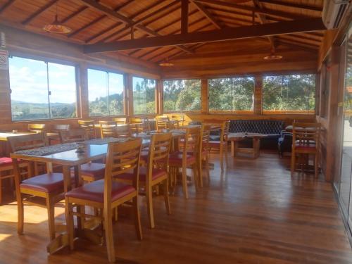 a dining room with tables and chairs and windows at Pousada Vale Do Comandante in Macacos