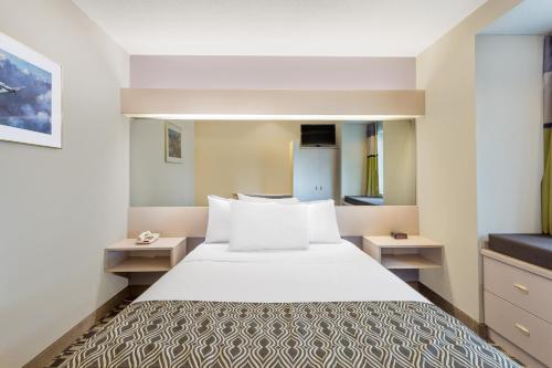 um quarto com uma grande cama branca e duas mesas em Microtel Inn & Suites by Wyndham em Sandston