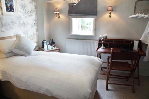 a bedroom with a bed and a desk and a chair at Flower Pot Hotel in Sunbury