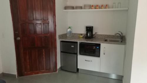 a kitchen with a door and a sink and a microwave at Hotel Gerald in Contadora