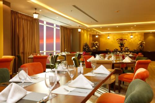 a dining room with tables and chairs and a restaurant at Swiss Flora Inn Hotel Riyadh in Riyadh