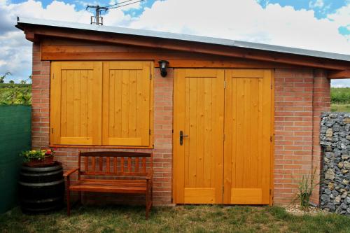 a shed with two wooden doors and a bench at Vinařský penzion Přední Hora in Velké Bílovice
