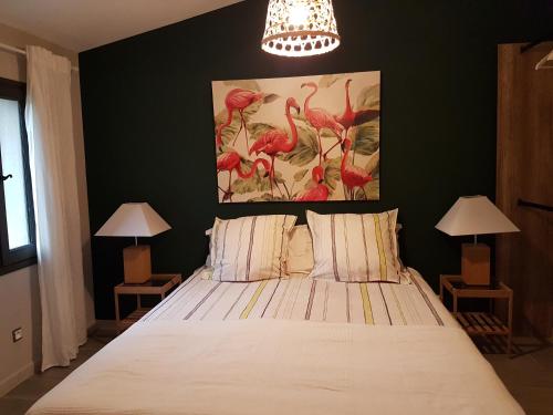 a bedroom with a bed with two lamps and a painting on the wall at les bignones in Uzès