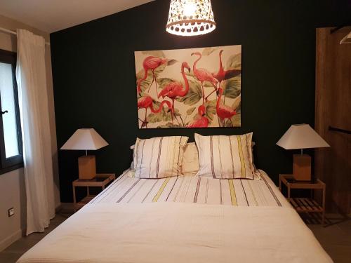 于捷斯的住宿－les bignones，一间卧室配有一张带两盏灯的床,墙上挂有一幅画