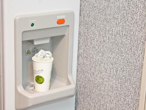 a drink dispenser in a refrigerator with a cup in it at Richmond Hotel Kochi in Kochi