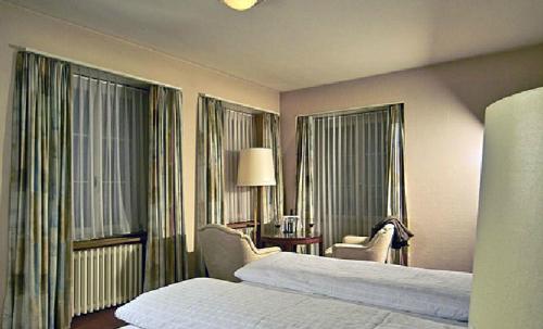 une chambre d'hôtel avec un lit, une chaise et des fenêtres dans l'établissement Hotel Krone, à Wangen an der Aare