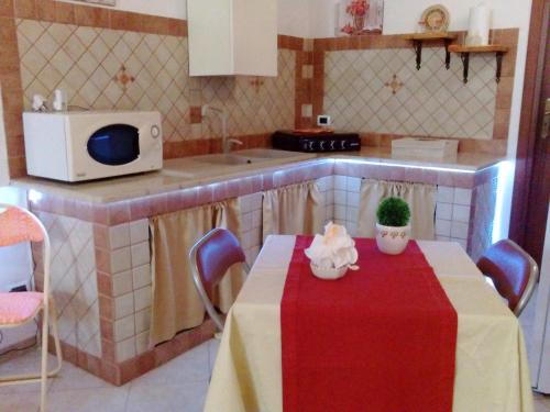 uma pequena cozinha com uma mesa com uma toalha de mesa vermelha em Relax Room em Mazara del Vallo