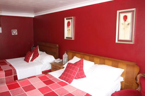 a bedroom with two beds and a red wall at Wrangham House in Filey
