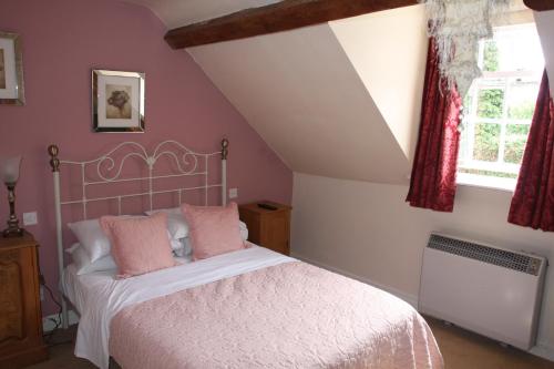 a bedroom with pink walls and a bed with pink pillows at Wrangham House in Filey