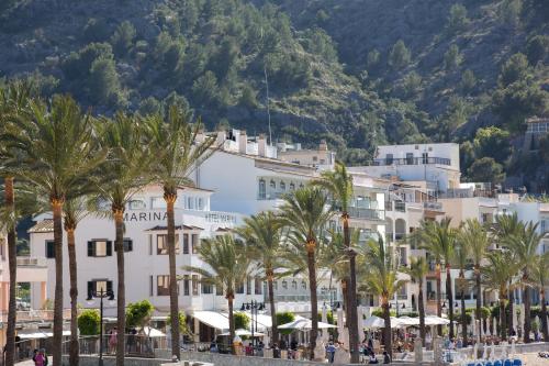 a group of buildings on a beach with palm trees at Hotel Marina in Port de Soller