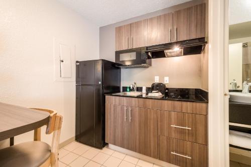 a kitchen with a black refrigerator and a table at Studio 6-Duluth, GA - Atlanta - Gwinnett Place in Duluth
