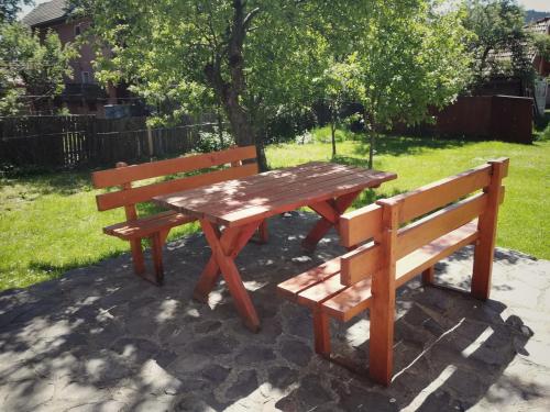 a picnic table and two benches in a park at Pensiunea Apolka Panzió in Covasna