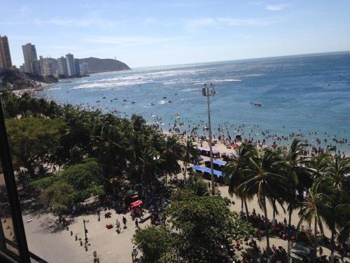 un grupo de personas en una playa con el océano en Apartamentos Osma, en Santa Marta