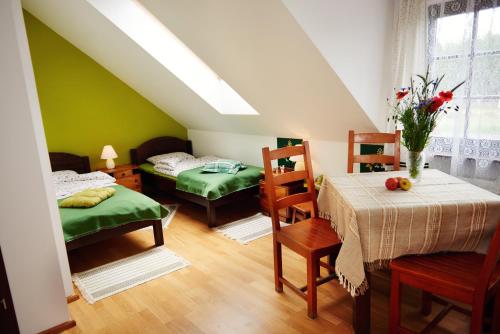 a room with two beds and a table and chairs at Willa Cicho Sza in Węgorzewo