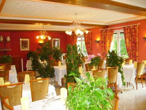 a dining room with white tables and green plants at La Pierre Lys in Quillan