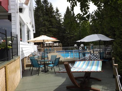 a patio with chairs tables and umbrellas next to a pool at Auberge Hotel Spa Watel in Sainte-Agathe-des-Monts