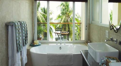 a bathroom with a tub and a sink and a window at Hotel La Gaviota Tropical in Playa Hermosa