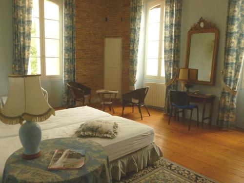 - une chambre avec un lit, un miroir et des chaises dans l'établissement Château Lagaillarde, à Thil