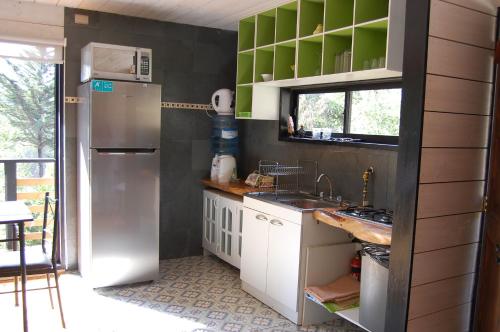 a small kitchen with a refrigerator and a sink at Cabaña del Bosque in Pichilemu