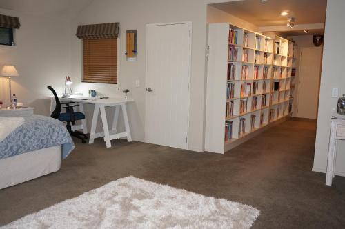 a bedroom with a bed and a desk and book shelves at Haven Suite Luxury 5 Star in Queenstown