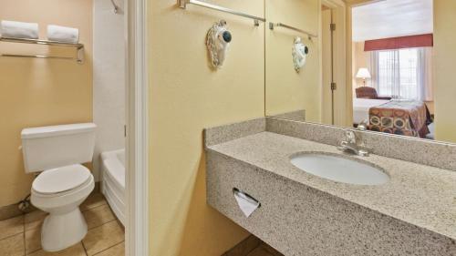 La salle de bains est pourvue de toilettes et d'un lavabo avec miroir. dans l'établissement Best Western Desert Inn, à Safford