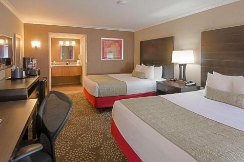 ユマにあるBest Western Yuma Mall Hotel & Suitesのベッド2台とデスクが備わるホテルルームです。