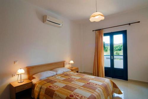 1 dormitorio con 1 cama y puerta corredera de cristal en Fotini Apartments, en Palaikastro