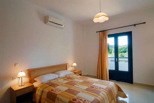 a bedroom with a bed and a sliding glass door at Fotini Apartments in Palekastron