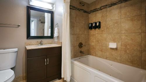 a bathroom with a tub and a toilet and a sink at Best Western Plus Diamond Valley Inn in Hemet