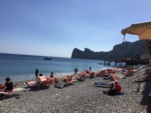 a group of people sitting on a beach at De Maria House in SantʼAgata sui Due Golfi