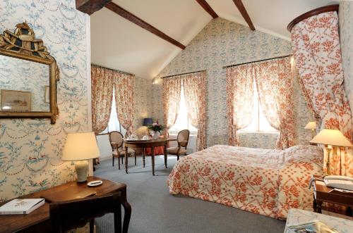 a bedroom with a bed and a desk and a table at Hôtellerie Du Bas-Bréau in Barbizon