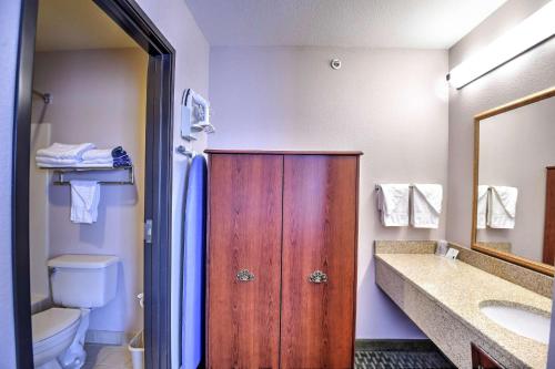 a bathroom with a wooden door and a toilet and a sink at SureStay Hotel by Best Western Ottawa in Ottawa