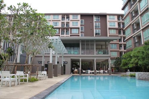 a hotel with a swimming pool in front of a building at Baan Peang Ploen B411 in Hua Hin