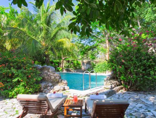a swimming pool with two chairs and a table next to it at Hacienda San Jose Cholul in Tixkokob