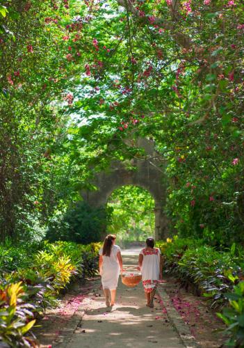 a woman and boy walking down a path with baskets at Hacienda San Jose Cholul in Tixkokob
