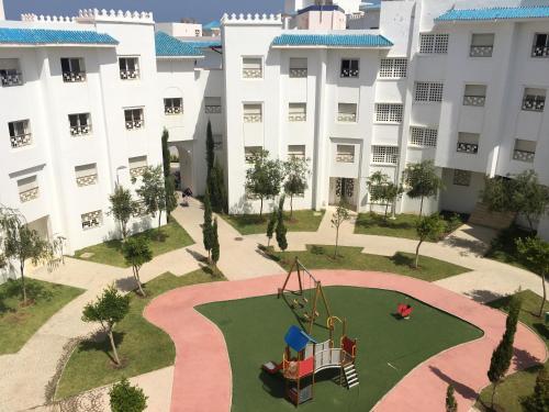 an apartment building with a playground in the courtyard at Résidence Bab Sebta in Fnidek