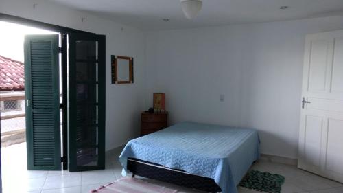 a bedroom with a bed and a door with a window at Casa Angra Itanema in Angra dos Reis