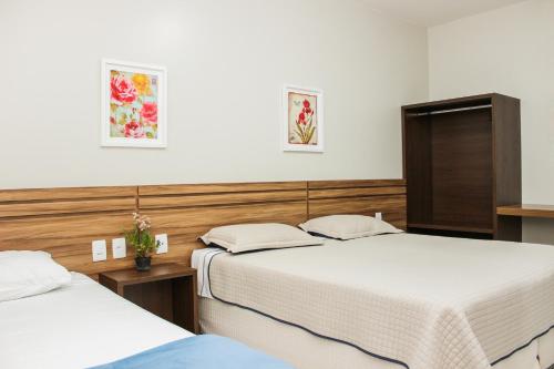 two beds in a hotel room with two beds at Hotel São Miguel in Sorriso