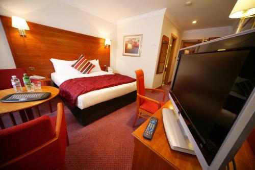 a hotel room with a bed and a flat screen tv at Mercure York Fairfield Manor Hotel in York