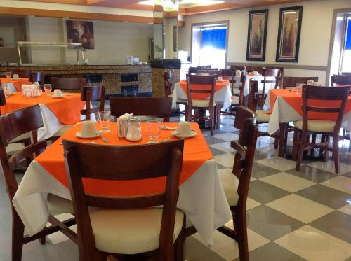 a dining room with tables and chairs with orange table cloth at Best Western Hotel Plaza Matamoros in Matamoros