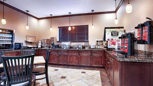 a kitchen with wooden cabinets and a table and chairs at Best Western Plus Royal Mountain Inn & Suites in Athens