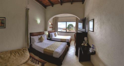 a hotel room with two beds and a window at Best Western Taxco in Taxco de Alarcón