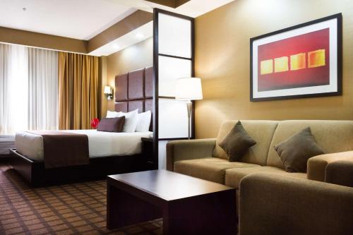 a hotel room with a bed and a couch at Best Western PREMIER Monterrey Aeropuerto in Monterrey
