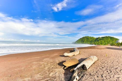 a beach with some logs and rocks on the sand at Best Western Jaco Beach All Inclusive Resort in Jacó