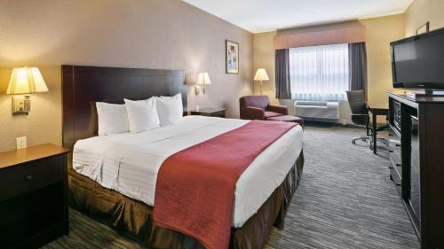 a hotel room with a bed and a flat screen tv at Best Western Dayton Inn & Suites in Dayton