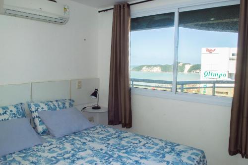 a bedroom with a bed and a window with a view of the ocean at Apartamento Deluxe Ahead Ponta Negra in Natal