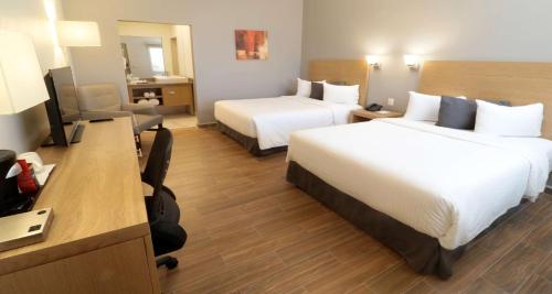 a hotel room with two beds and a desk at Bluu Hotel Aeropuerto Monclova-Frontera in Monclova
