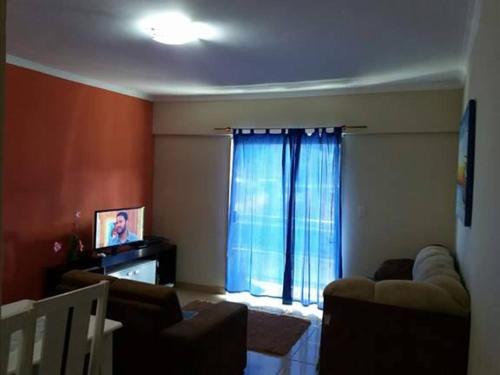 sala de estar con sofá, TV y ventana en Apartamento Murimar XIII en Vila Muriqui