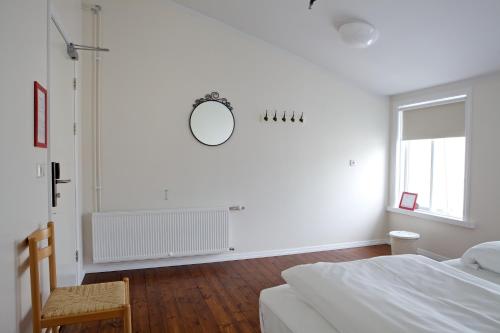 a white bedroom with a bed and a mirror on the wall at Akureyri Backpackers in Akureyri
