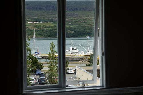 a window with a view of a harbor and a boat at Akureyri Backpackers in Akureyri